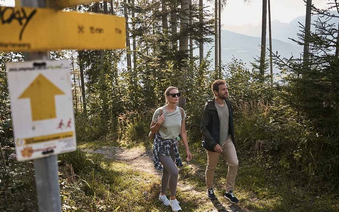 Paar auf Wanderschaft in den Bergen mit Wegweiser im Vordergrund